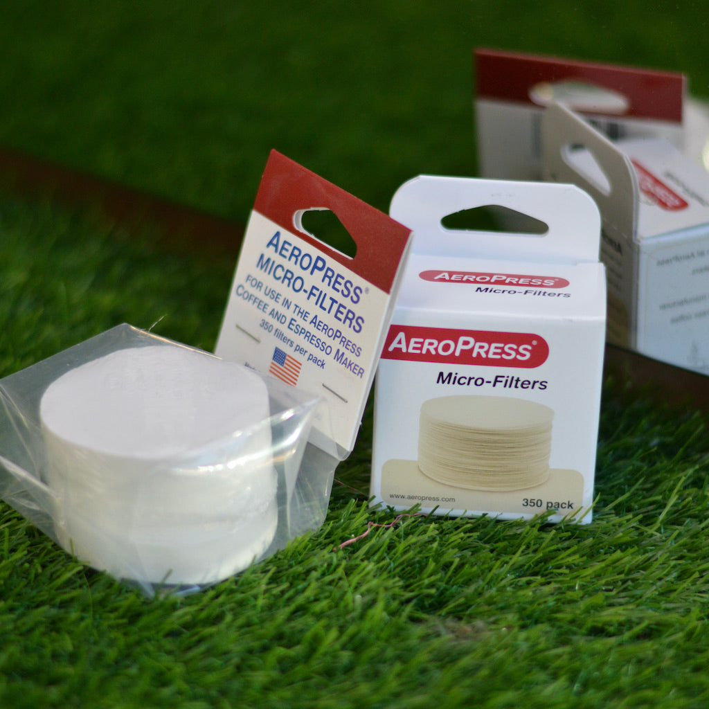 Aeropress filter papers in two different packaging styles, one in a plastic pack, one in a paper box